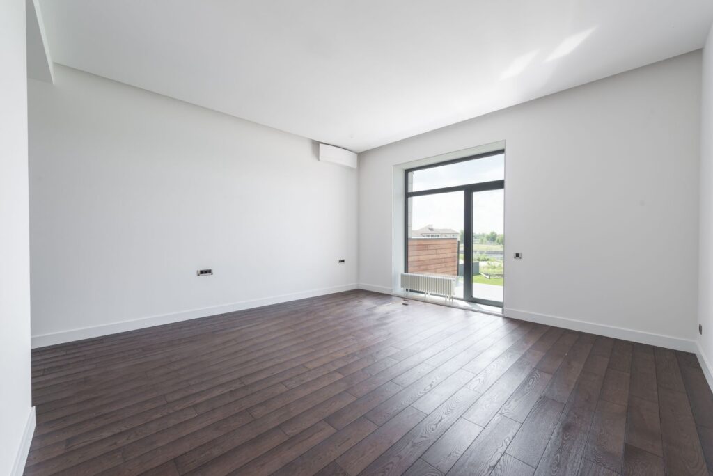 Apartament gol, luminos, cu parchet și fereastră deschisă, pregătit pentru vizionare
