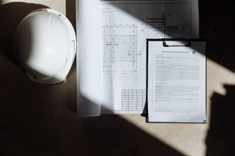 Deviz de lucrări tipărit, un calculator și planuri de construcție pe o masă de birou