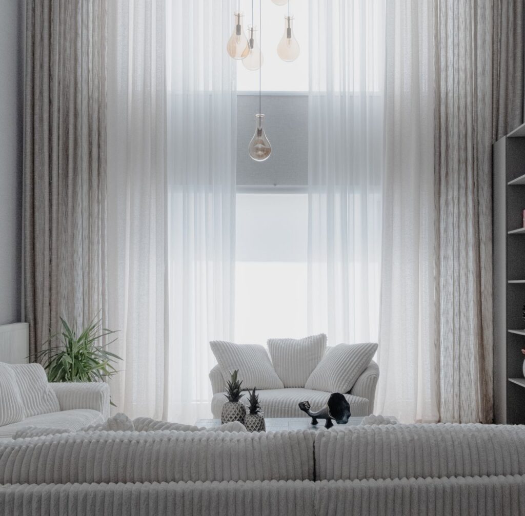 Living luminos amenajat cu canapea deschisă la culoare, covor, plante și mobilier din lemn